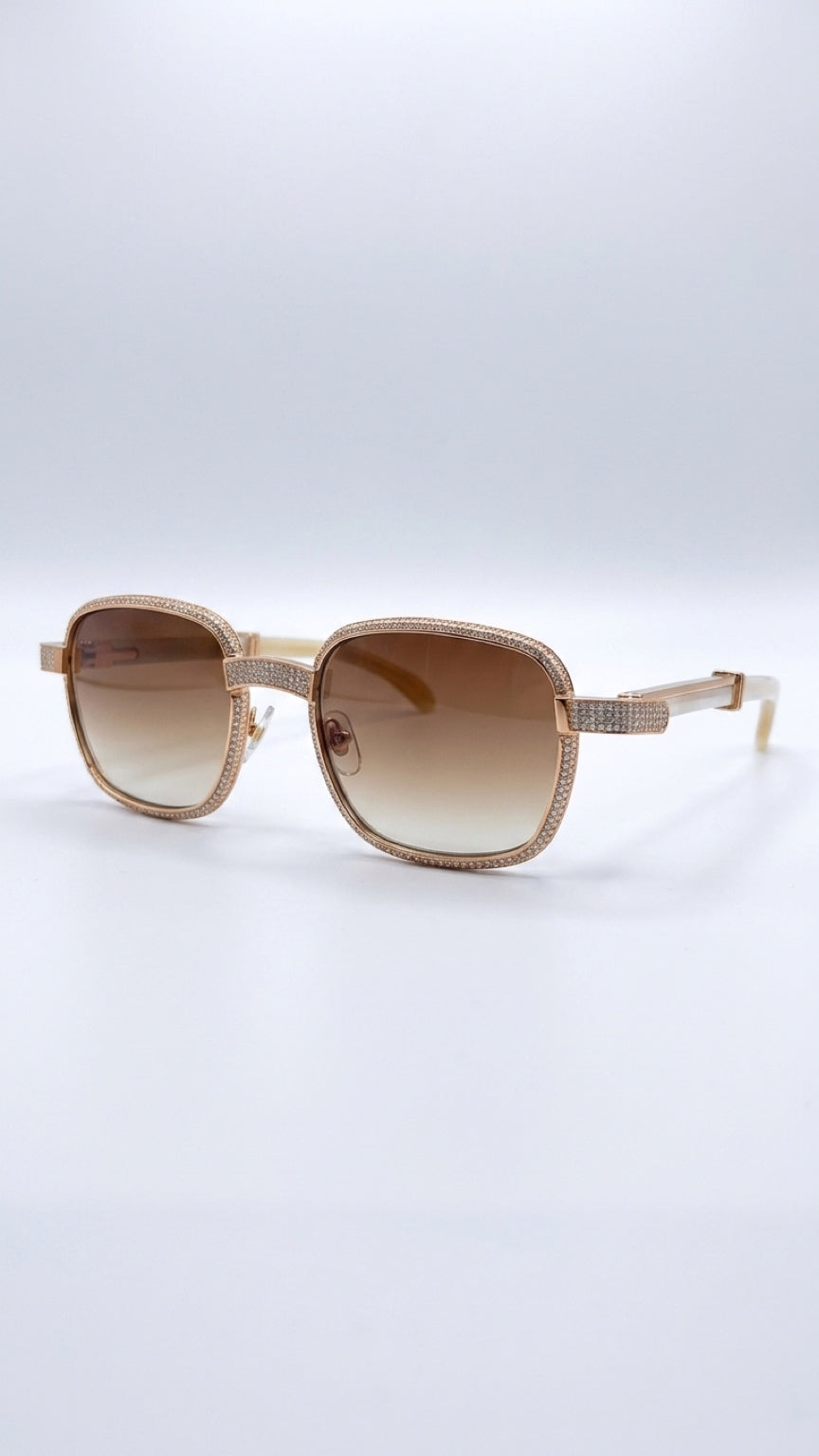 Oversized square sunglasses with a gold-tone metal frame, textured rhinestone trim, and brown gradient lenses, shown on a light gray studio background.