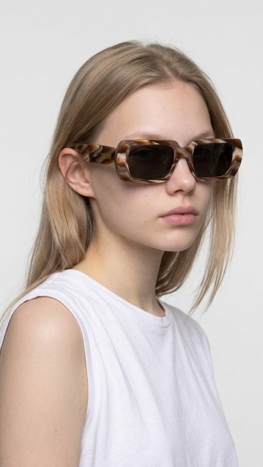 Woman wearing CONFILVARO oversized brown tortoiseshell-effect rectangle sunglasses with dark lenses
