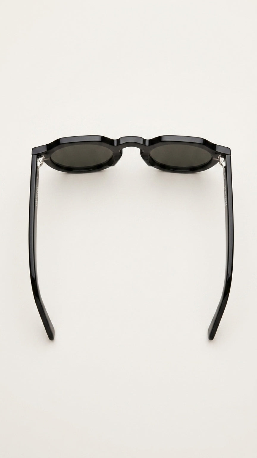 Black oval sunglasses with dark lenses and thin arms, photographed from the back on a light gray background.