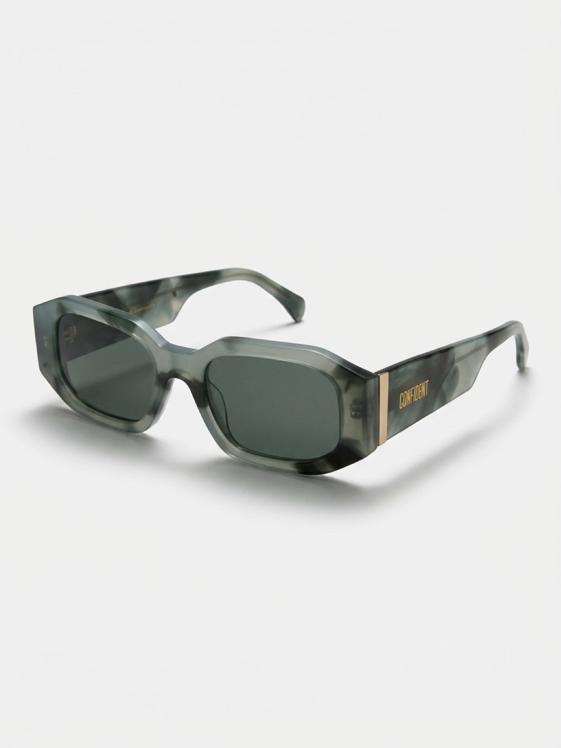 A pair of Off-White sunglasses featuring a translucent gray-green and black tortoiseshell acetate frame with dark green lenses and gold branding on the temple arm, set against a light gray background.